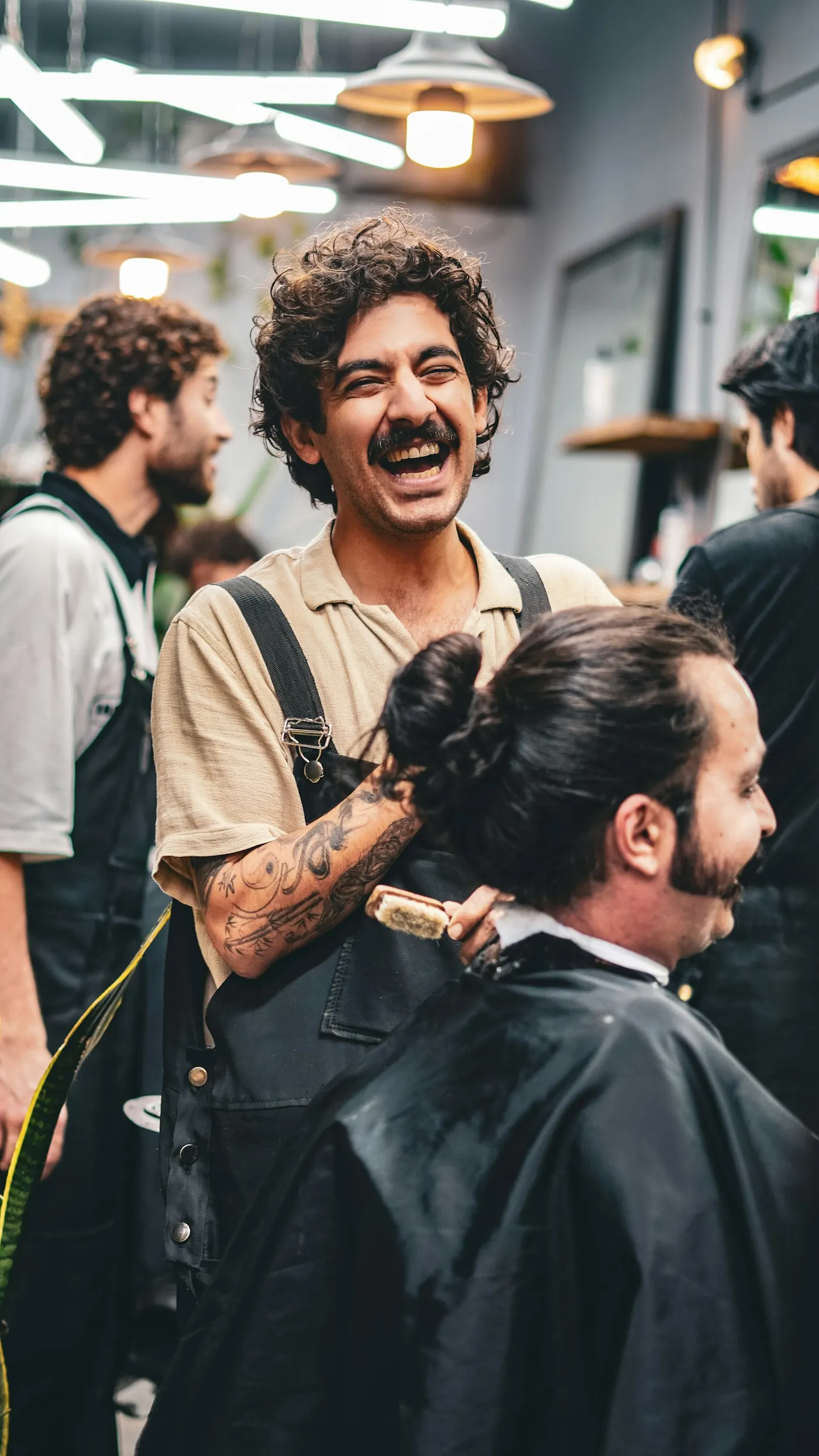 Barbero riéndose mientras le corta el pelo a un cliente en su barbería